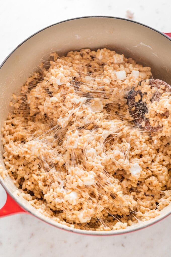 Gooey mixture for brown butter rice Krispie treats being stirred together in a large pan.