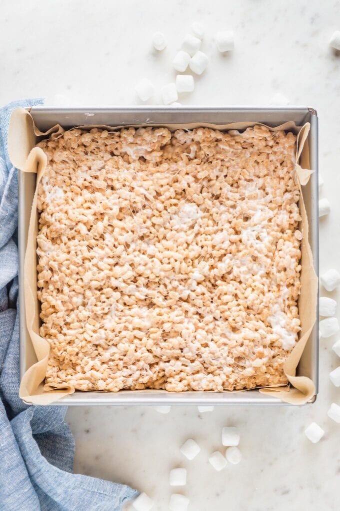 Rice Krispies mixture pressed into a square metal baking pan.