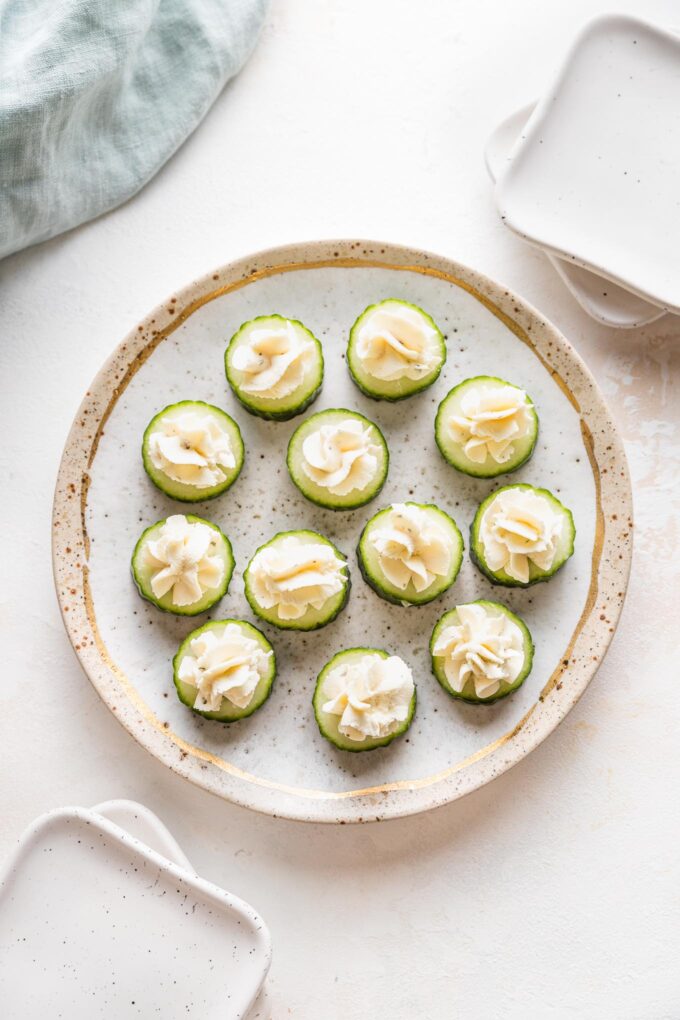 Pretty gold rimmed plate with Boursin cucumber bite appetizers.
