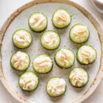 Pretty gold rimmed plate with Boursin cucumber bite appetizers.