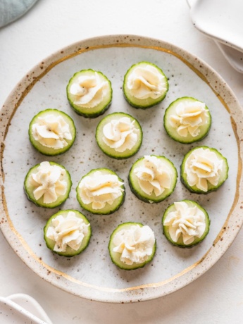 Pretty gold rimmed plate with Boursin cucumber bite appetizers.