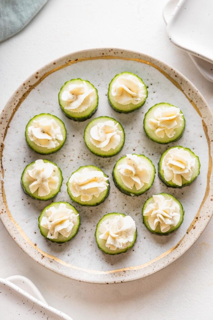 Pretty gold rimmed plate with Boursin cucumber bite appetizers.