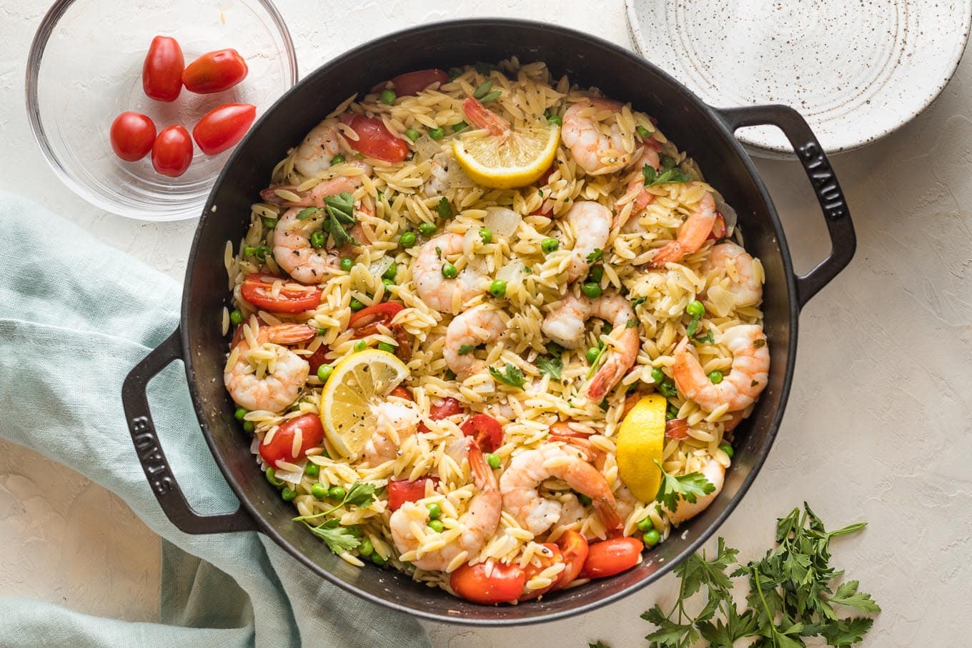 Finished skillet with shrimp and lemon wedges and herbs added back to orzo in skillet.