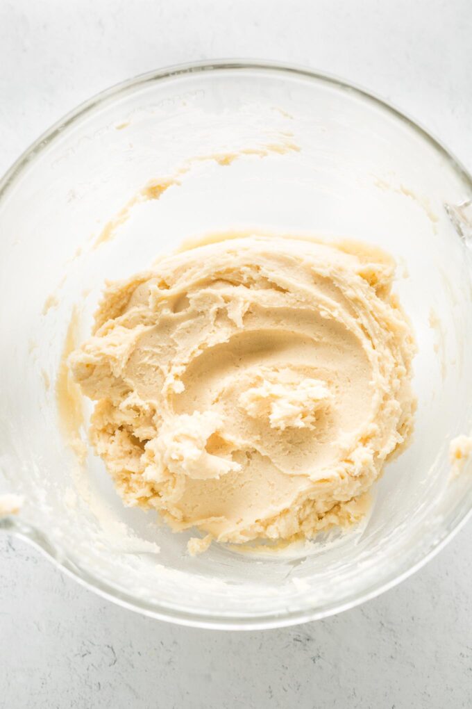 Close-up of soft sugar cookie dough in a clear glass bowl.