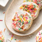 Small plate of soft frosted sugar cookies with multi-colored sprinkles.