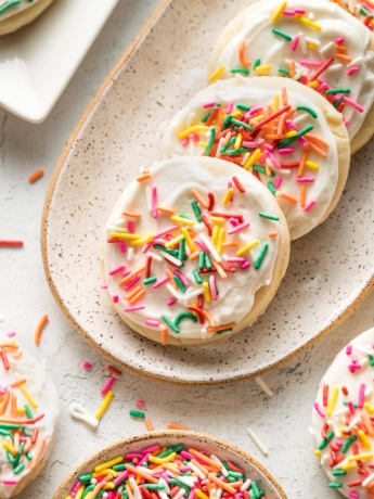 Small plate of soft frosted sugar cookies with multi-colored sprinkles.