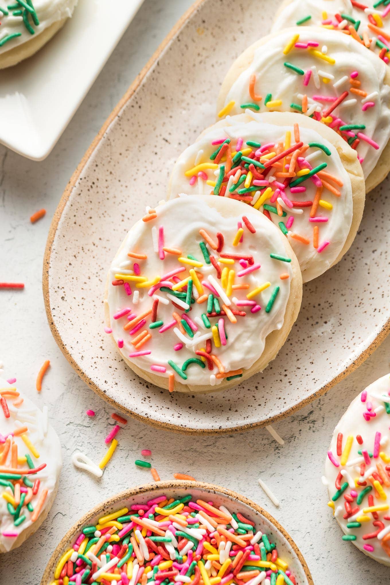 Small plate of soft frosted sugar cookies with multi-colored sprinkles.
