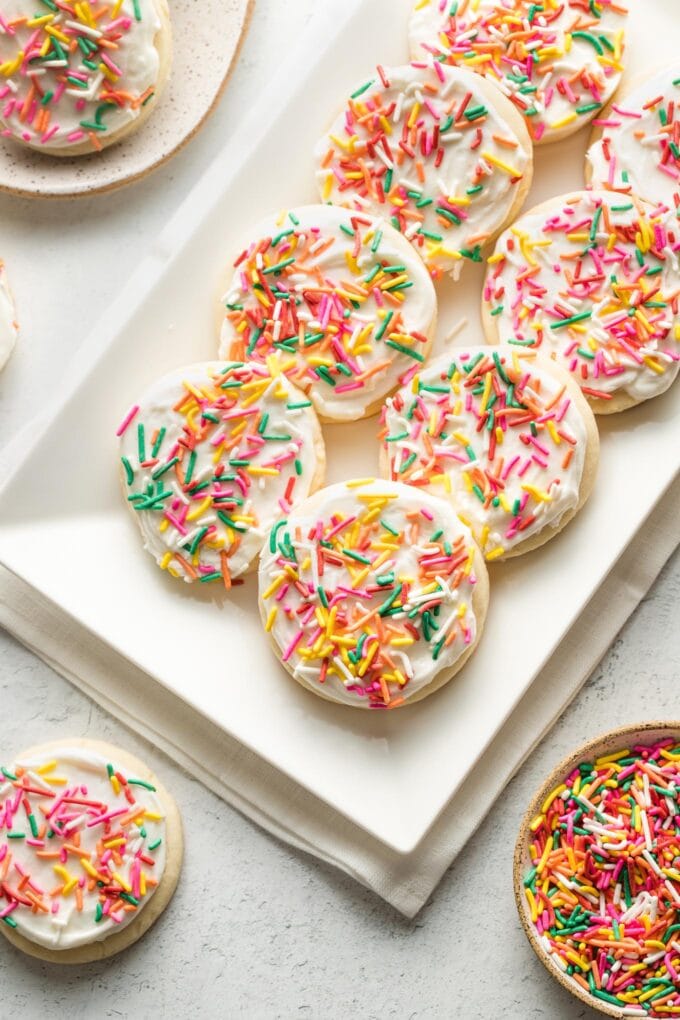 White plate filled with soft frosted sugar cookies, ready to share.