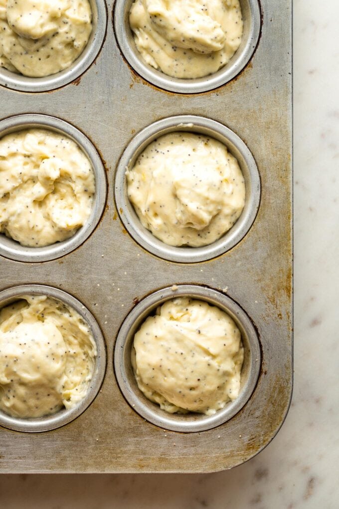Muffin batter divided among wells of a baking tin.