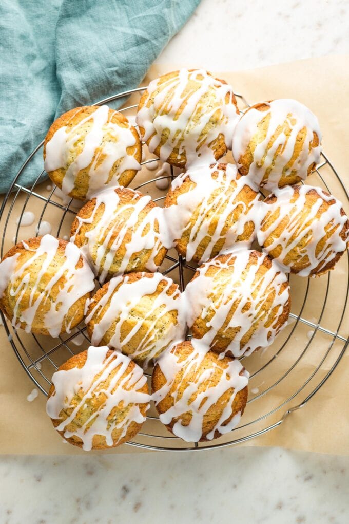 Glazed lemon poppy seed muffins on a cooling rack.