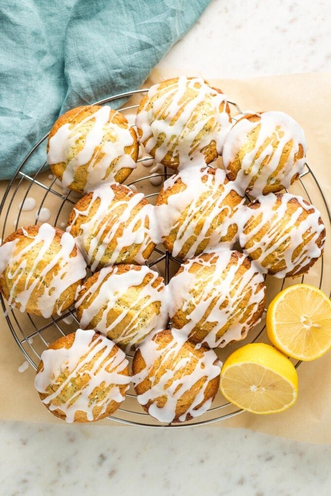 Glazed lemon poppy seed muffins on a cooling rack.