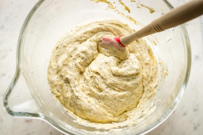 Batter for lemon poppy seed muffins in a glass mixing bowl.