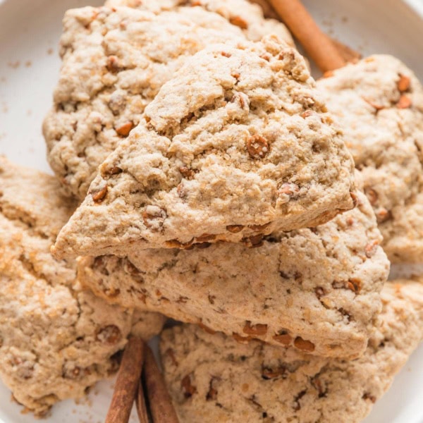 Close up of a cinnamon scone with cinnamon chips on a white plate.