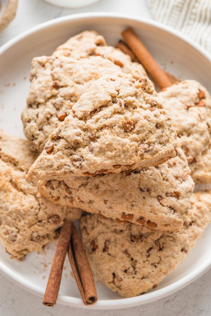 Close up of a cinnamon scone with cinnamon chips on a white plate.