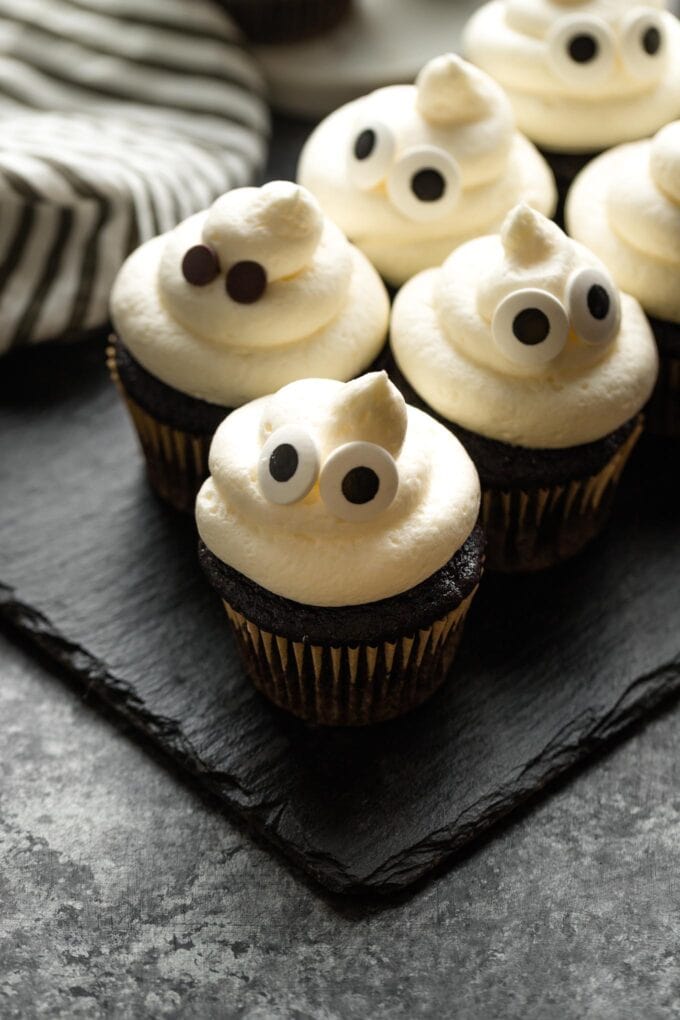 Ghost cupcakes arranged on a slate board.