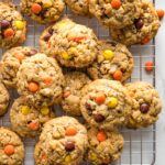 Monster cookies with Reese's pieces on a cooling rack.