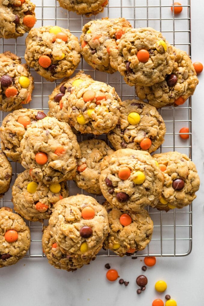 Monster cookies with Reese's pieces on a cooling rack.