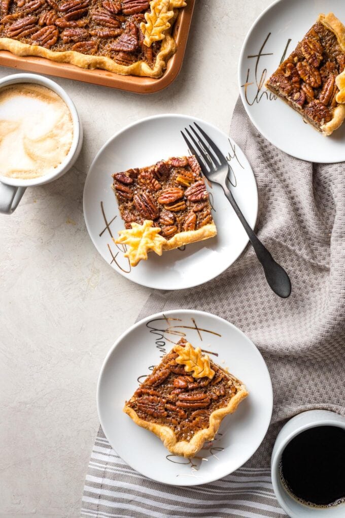 Scene of multiple plates with slab pecan pie served with coffee.