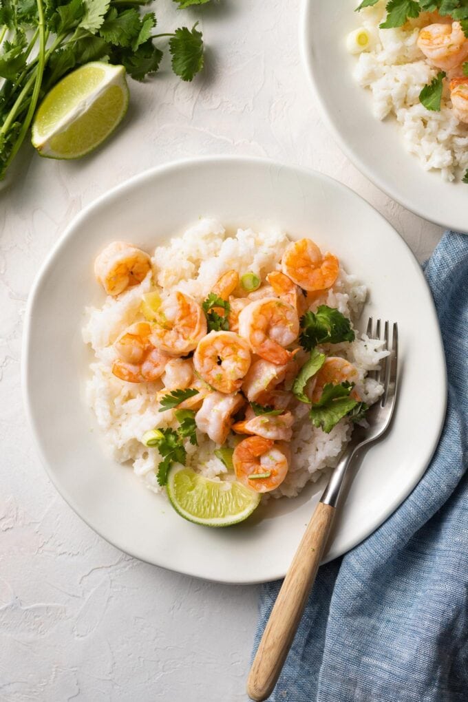Small white plate with garlic lime shrimp, coconut rice, cilantro and green onions.