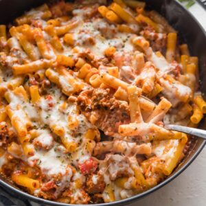 Piping hot cast iron skillet full of baked ziti with Italian sausage.