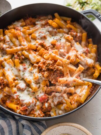 Piping hot cast iron skillet full of baked ziti with Italian sausage.