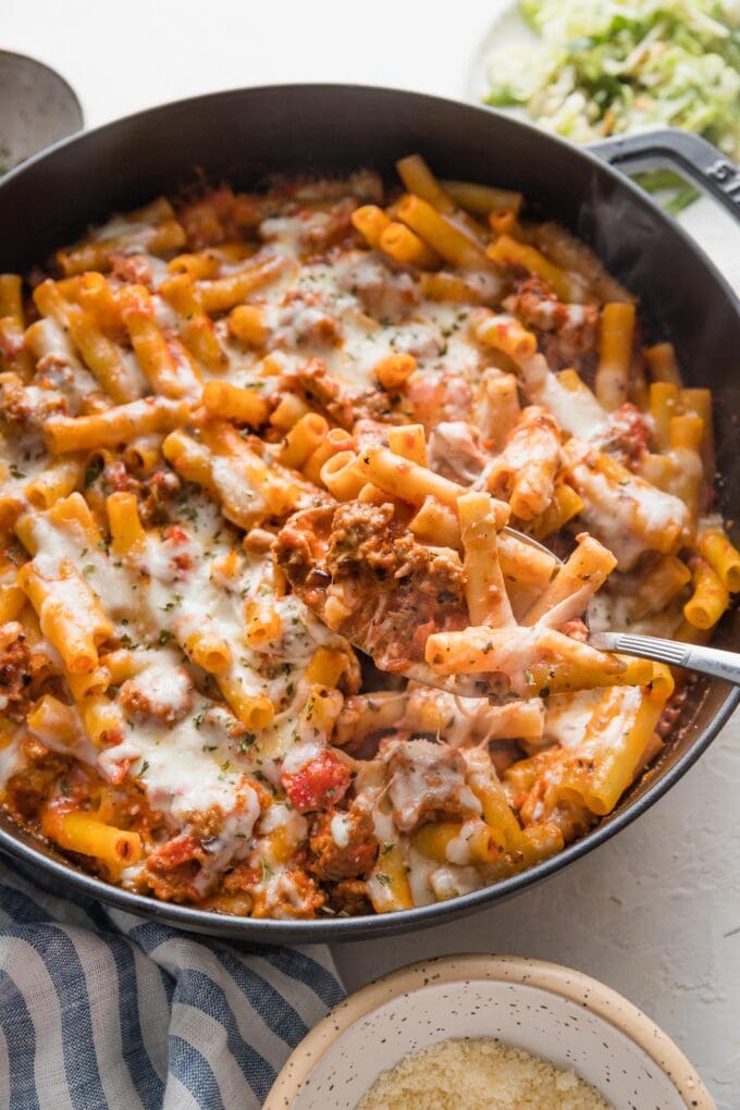 Piping hot cast iron skillet full of baked ziti with Italian sausage.