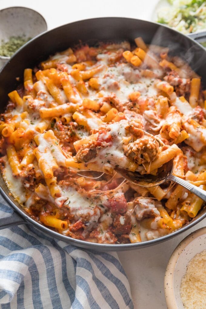 Close up of stretchy mozzarella cheese being pulled across a serving of hot baked ziti.