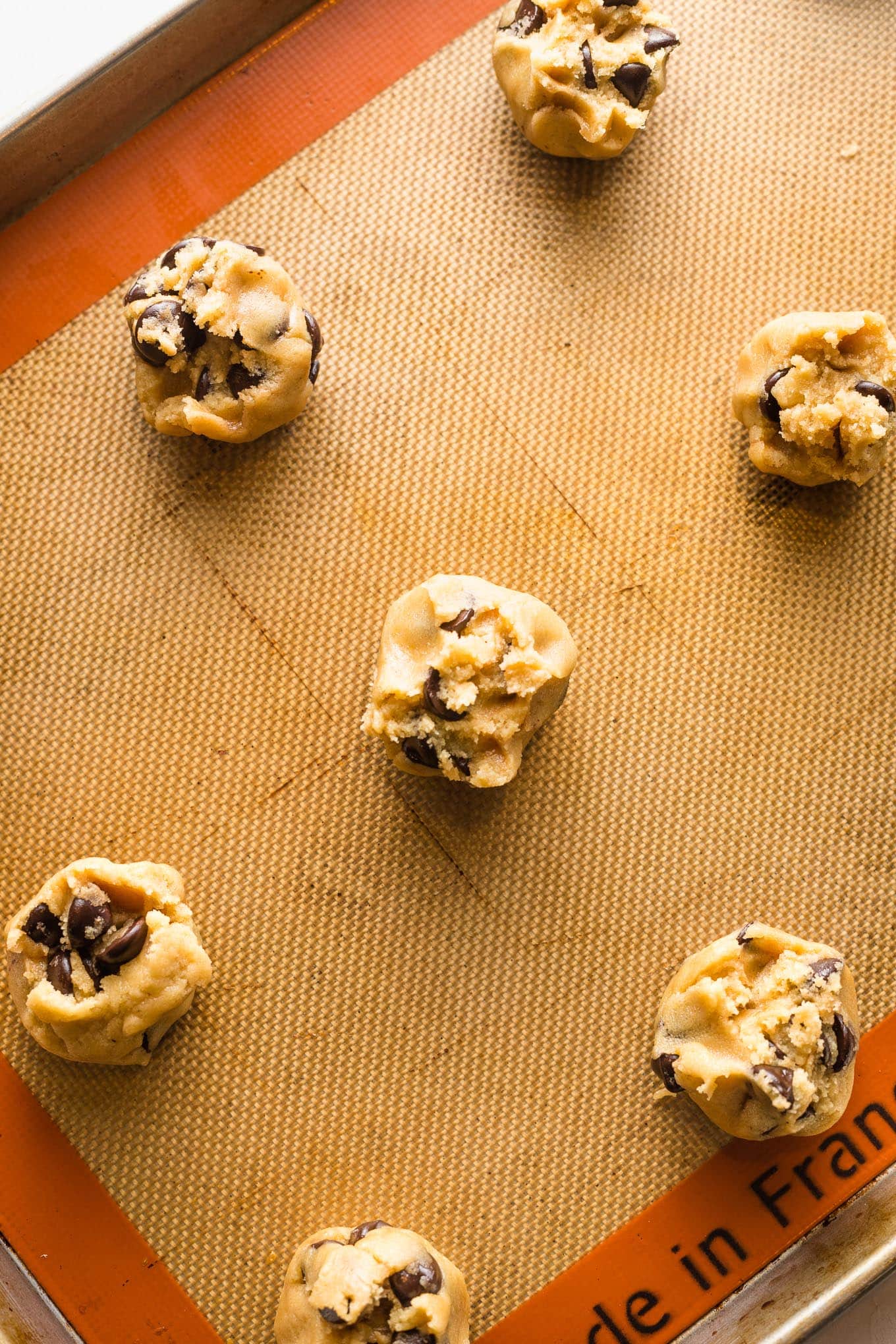 Cookie dough balls pulled apart so that a jagged edge is facing up before baking.