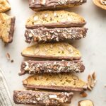 Row of chocolate-dipped almond biscotti lined up on parchment paper.