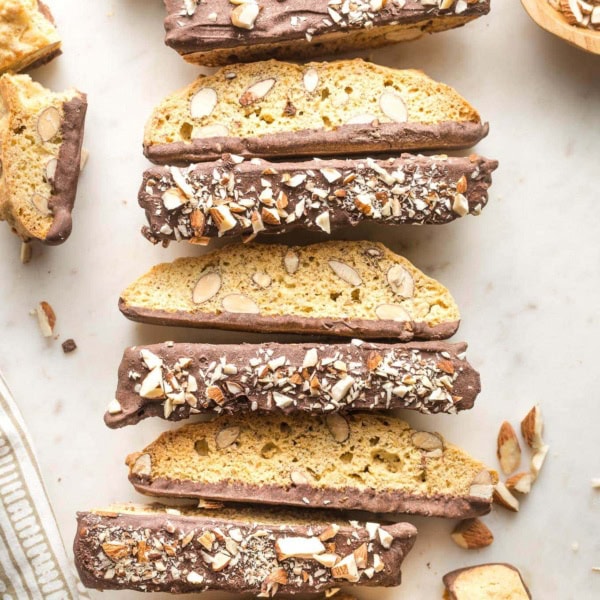 Row of chocolate-dipped almond biscotti lined up on parchment paper.