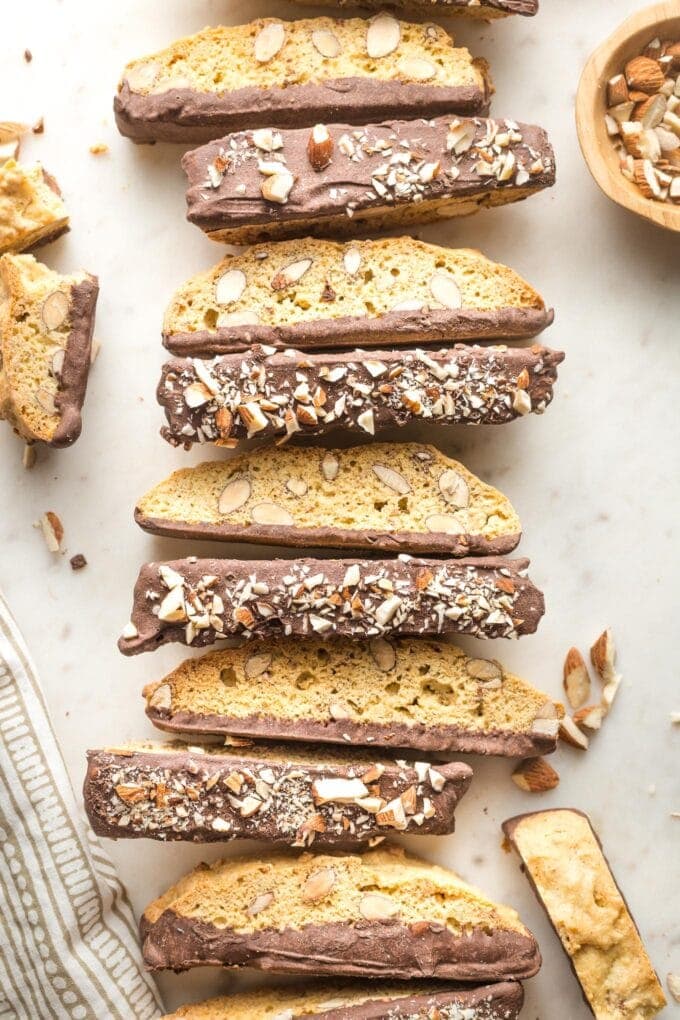 Row of chocolate-dipped almond biscotti lined up on parchment paper.