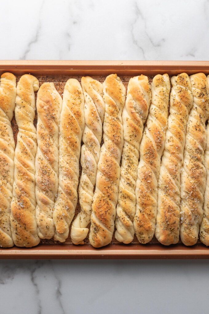 Just-baked breadsticks on baking sheet.