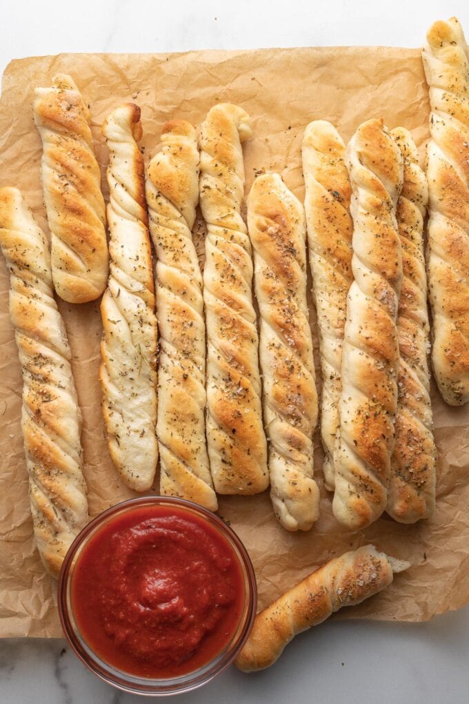 Soft garlic breadsticks laid out on parchment paper.
