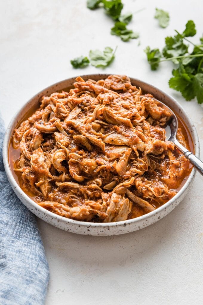 Serving bowl full of Instant Pot chicken Tinga with a smoky tomato sauce.