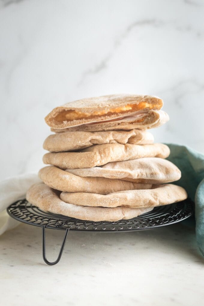 Stack of homemade whole wheat pita bread on a cooling rack.