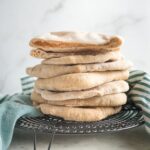 Stack of homemade whole wheat pita bread on a cooling rack.