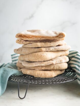 Stack of homemade whole wheat pita bread on a cooling rack.