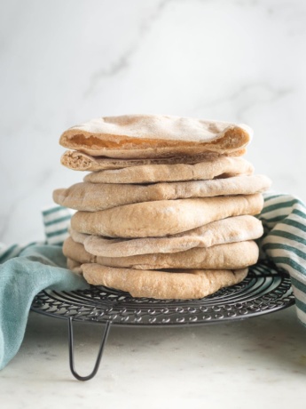 Stack of homemade whole wheat pita bread on a cooling rack.