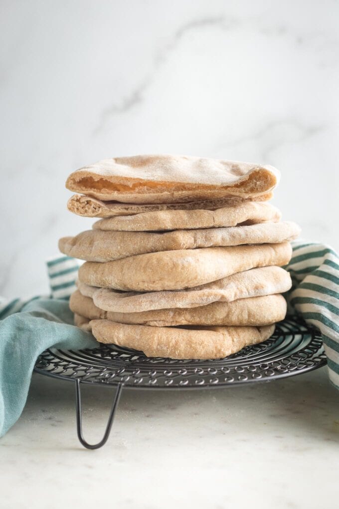 Stack of homemade whole wheat pita bread on a cooling rack.
