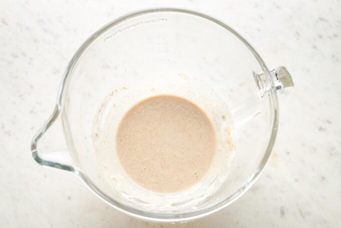 Small amount of flour, water, yeast, and honey mixed together in a clear mixing bowl.