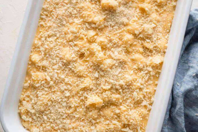 Breadcrumbs sprinkled on top of mac and cheese in a large rectangular baking pan.
