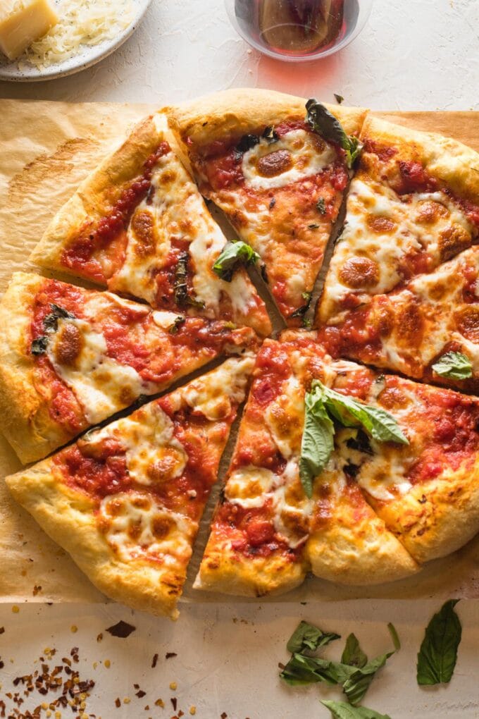 Homemade margherita pizza, fresh out of the oven, sliced and topped with fresh basil.