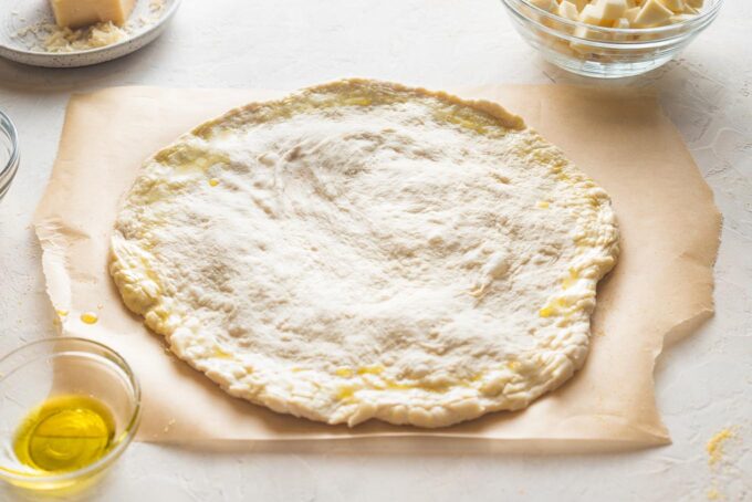 Shaped pizza crust brushed with olive oil on the outer rim.