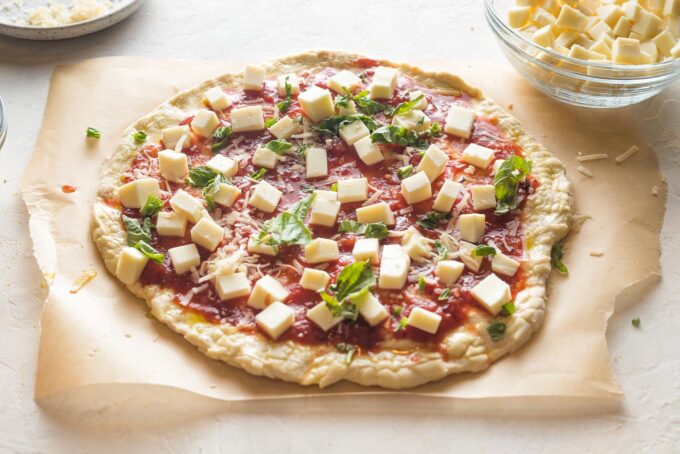 Homemade margherita pizza topped and ready to bake.