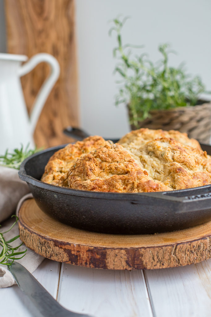 A side-view of savory soda bread baked in a cast-iron skillet, cooling on the counter.