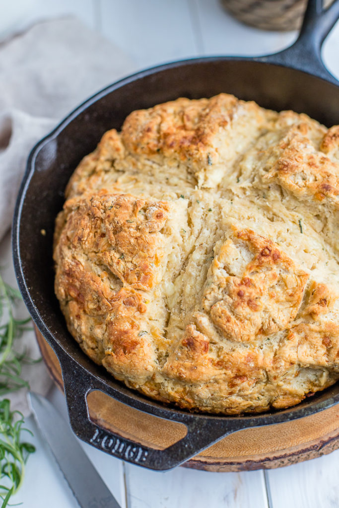 Rosemary cheddar Irish soda bread fully baked in a black cast-iron skillet.