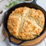 Rosemary cheddar Irish soda bread fully baked in a black cast-iron skillet.