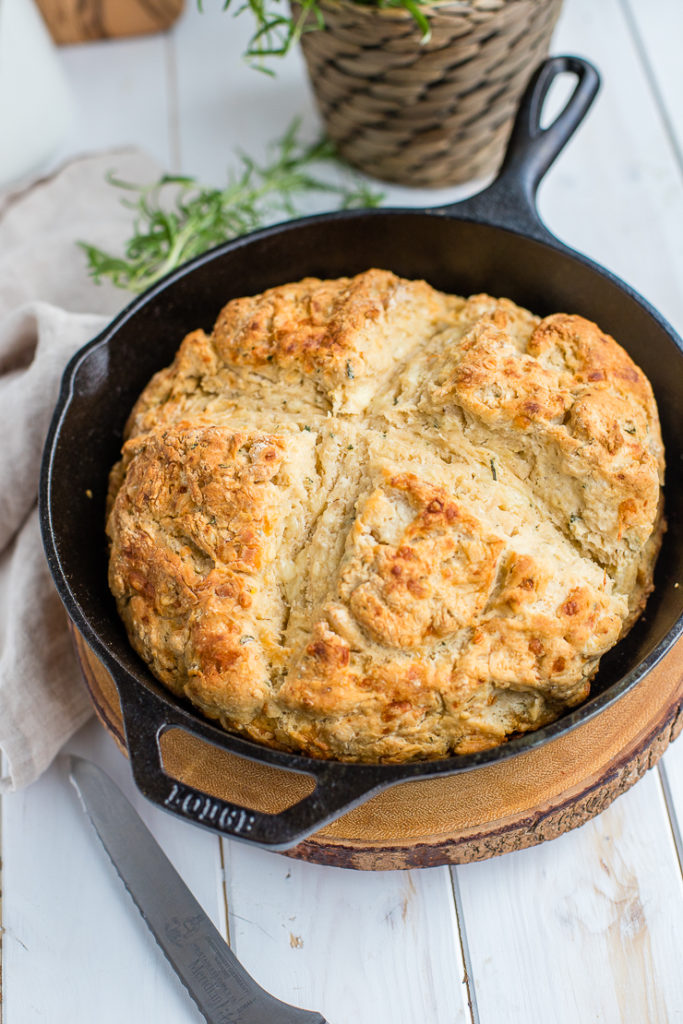 Rosemary cheddar Irish soda bread fully baked in a black cast-iron skillet.