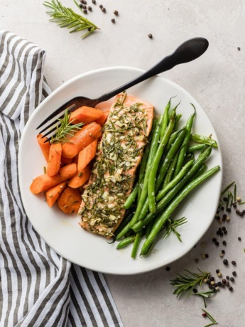 A plate of rosemary garlic salon with carrots and green beans.