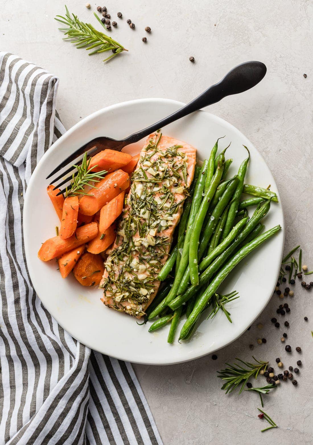 A plate of rosemary garlic salon with carrots and green beans.